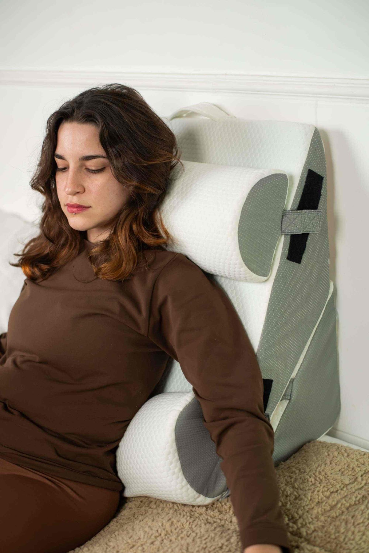 Woman reclining against the wedge pillow set while resting in bed